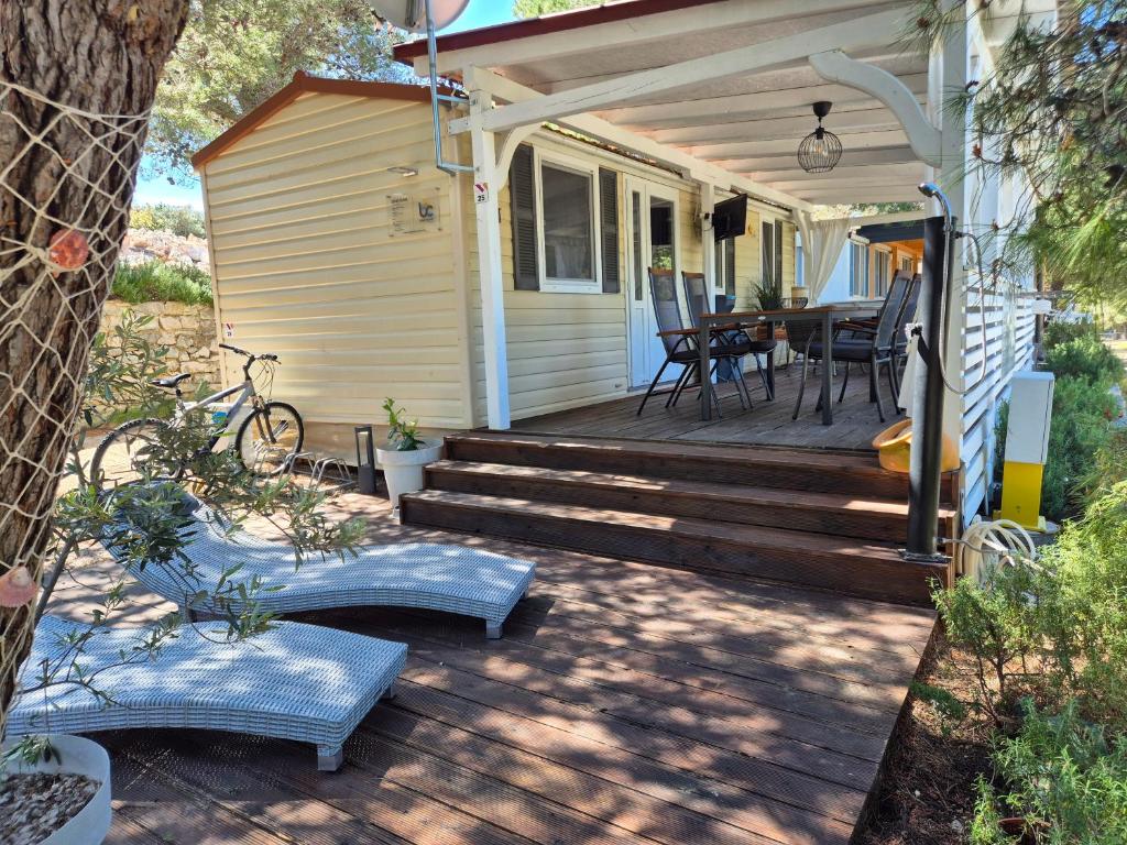 a porch of a house with stairs and a table at Mobile home BLUE CLASS B4 in Jezera