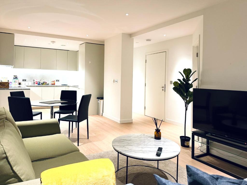 - un salon avec un canapé, une télévision et une table dans l'établissement Upper Riverside O2 2Bedroom Flat 05, à Londres