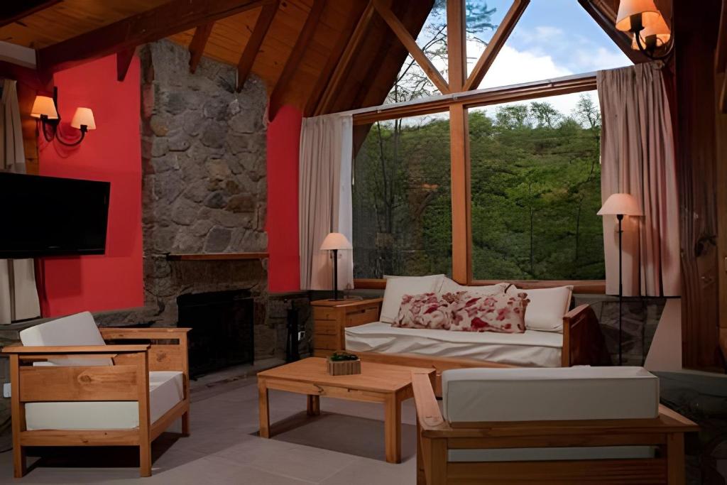 uma sala de estar com um sofá e uma grande janela em Cabaña Bosque y Río em Ushuaia