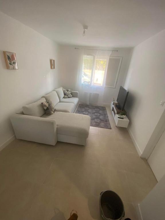 un salon blanc avec un canapé et une télévision dans l'établissement Joli appart proche de la mer, à Marseille