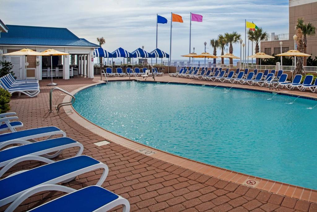 einen Pool mit blauen Stühlen und Sonnenschirmen in der Unterkunft SpringHill Suites by Marriott Virginia Beach Oceanfront in Virginia Beach