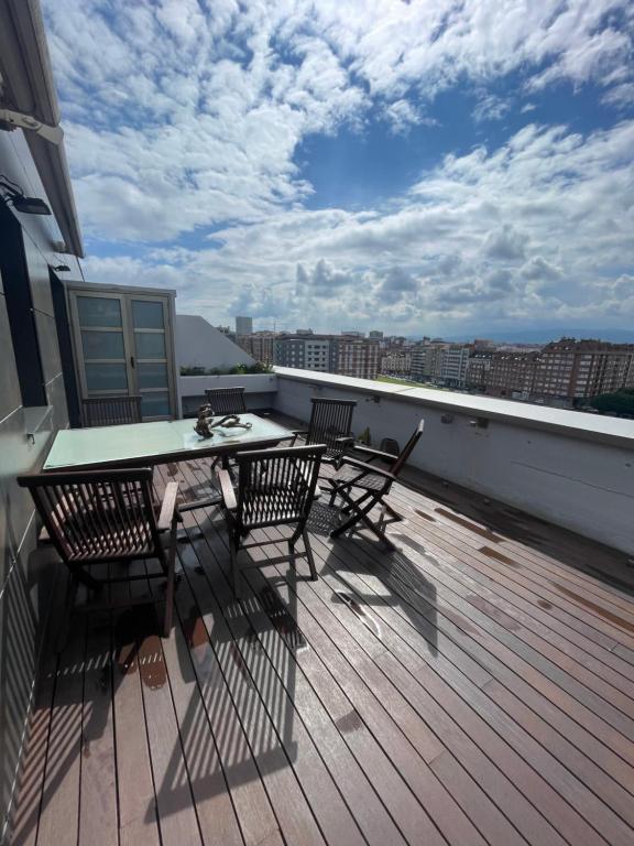 a balcony with a table and chairs on a roof at EL ÁTICO DE LA PLAYA Parking gratis in Gijón