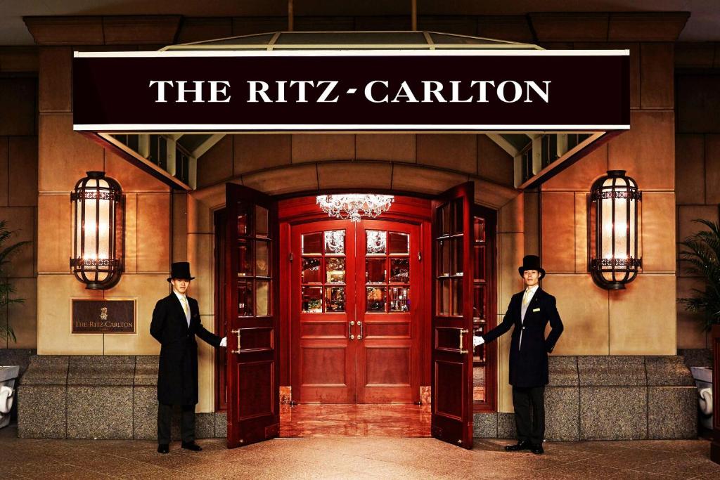 dos hombres con trajes parados frente a un edificio en The Ritz-Carlton Osaka, en Osaka