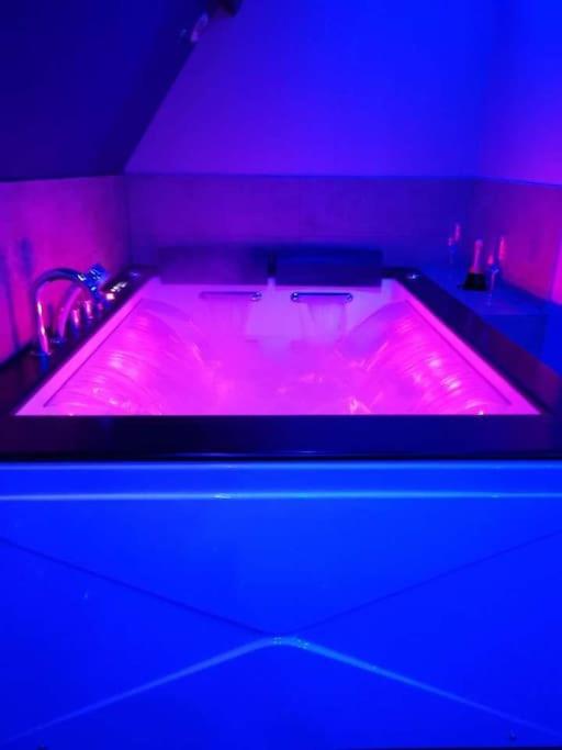 La salle de bains est pourvue d'une baignoire rose et d'un lavabo. dans l'établissement Gîte tout confort avec baignoire balneo', à Boos