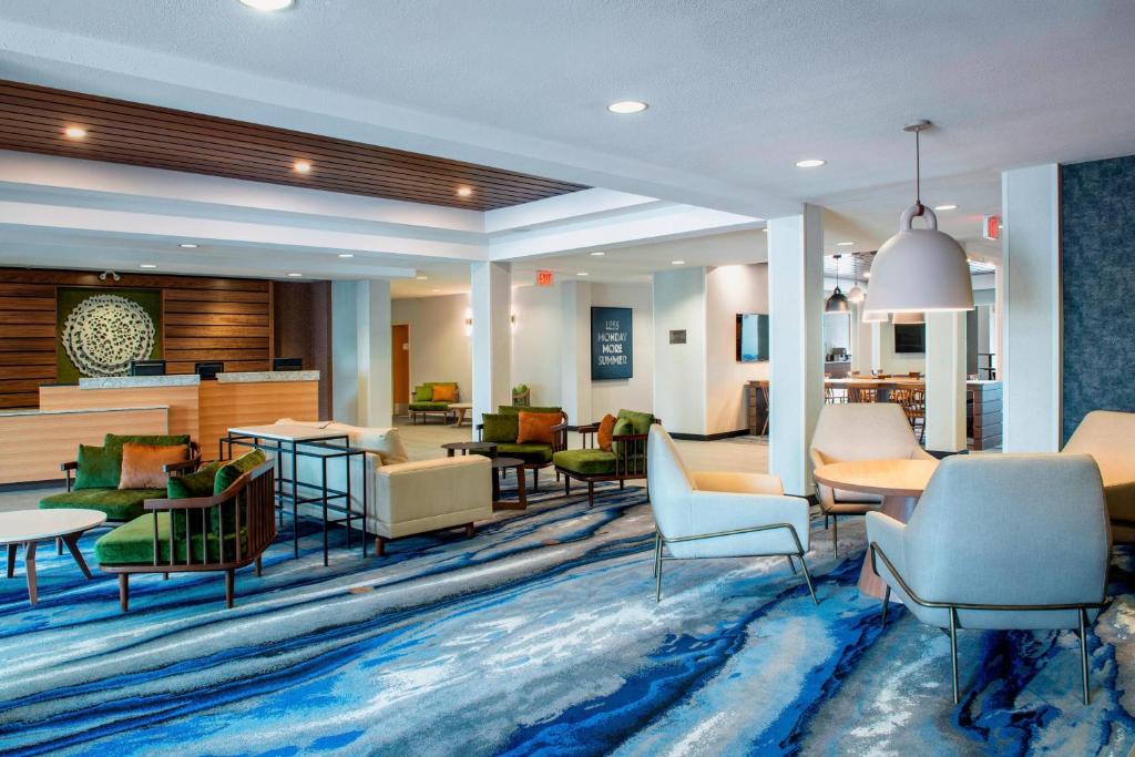 Fairfield Inn & Suites by Marriott Kelowna في كيلونا: لوبي فيه كنب وكراسي على سجادة زرقاء