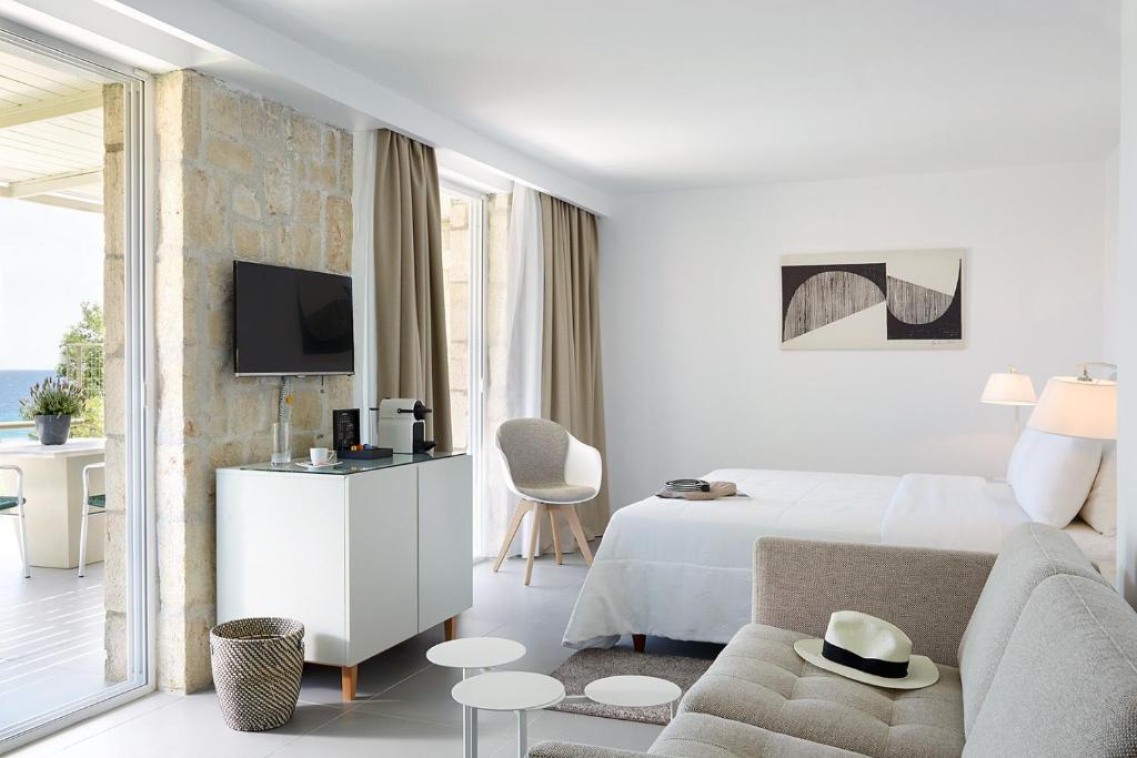 a white hotel room with a bed and a couch at Afitis Boutique Hotel in Afitos