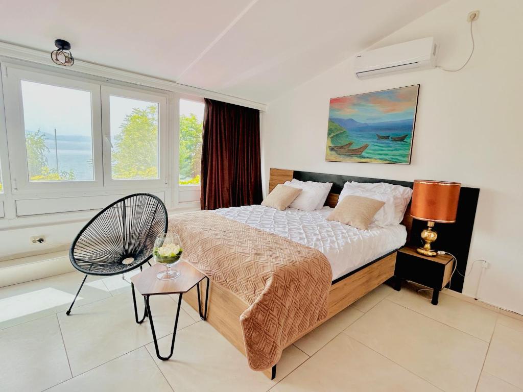 um quarto com uma cama, uma cadeira e janelas em Hotel Lagadin em Ohrid