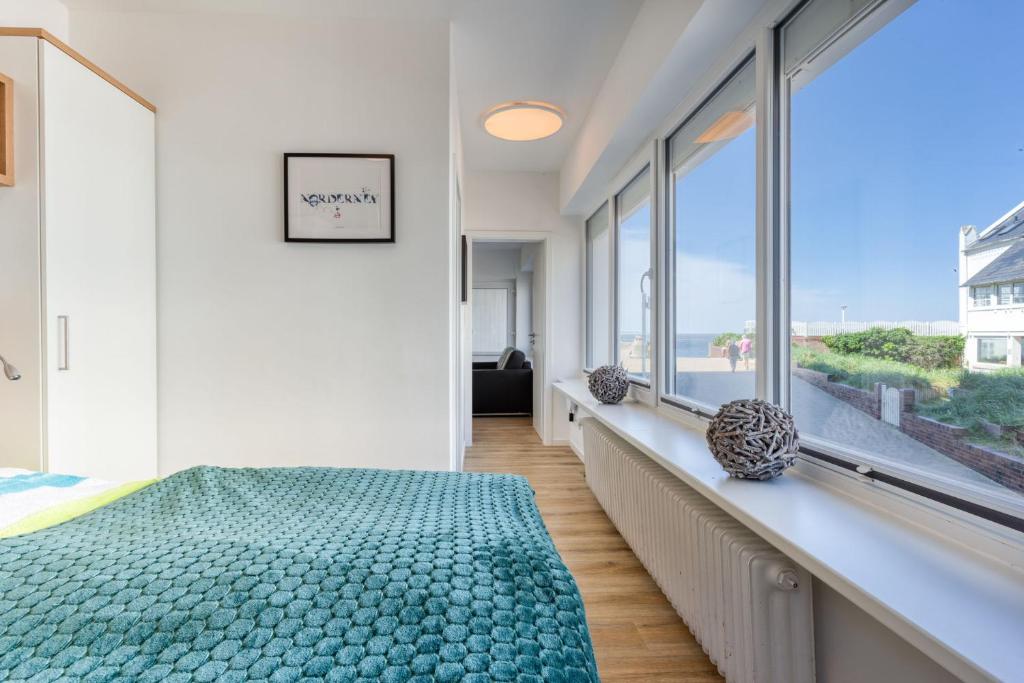 Schlafzimmer mit einem Bett und großen Fenstern in der Unterkunft Alte Teestube 69 2 Raum in Norderney