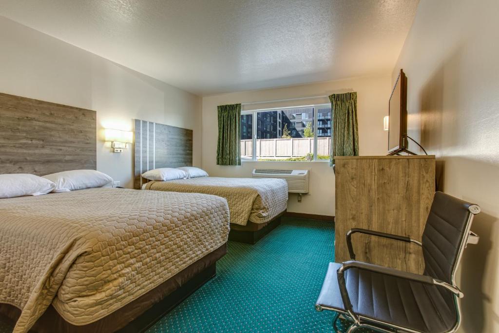 a hotel room with two beds and a chair at Coachman Inn in Bellingham