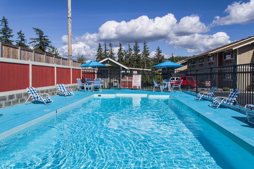una piscina en un hotel con sillas y sombrillas en Coachman Inn, en Bellingham