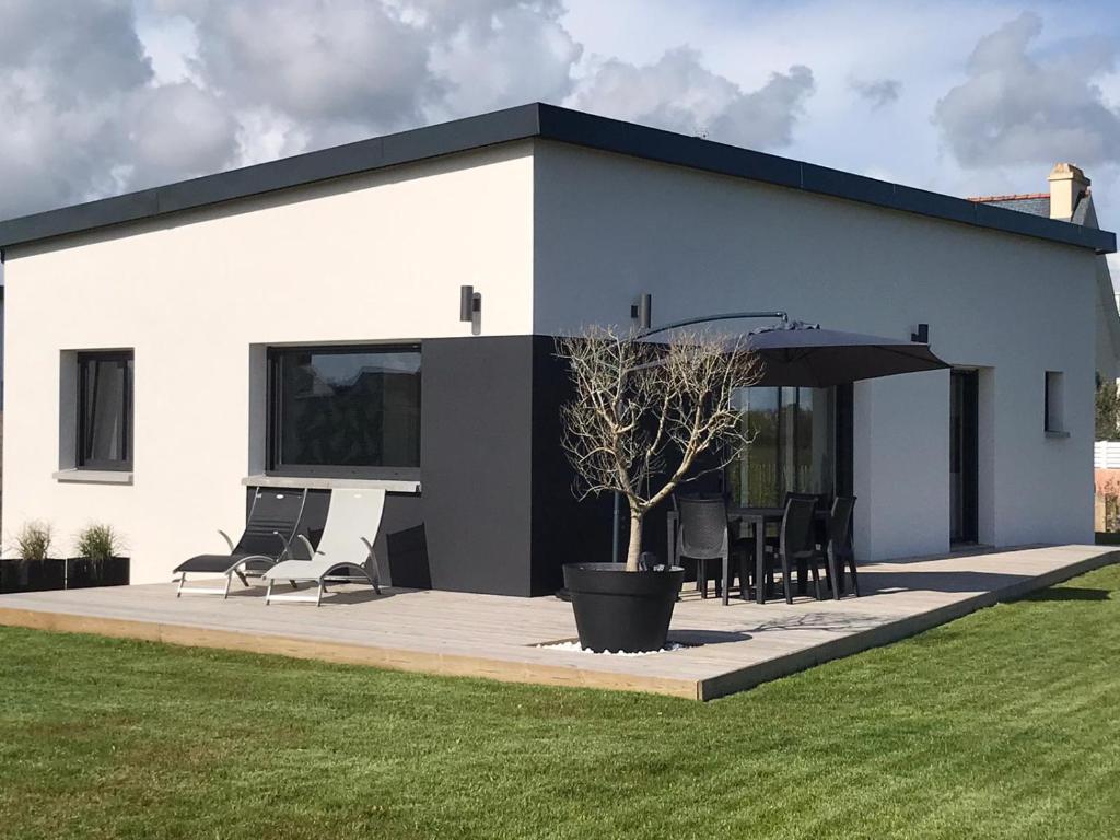 ein weißes Haus mit einer Terrasse mit Stühlen und einem Sonnenschirm in der Unterkunft Villa Ty Plad, Penmarc'h in Penmarcʼh