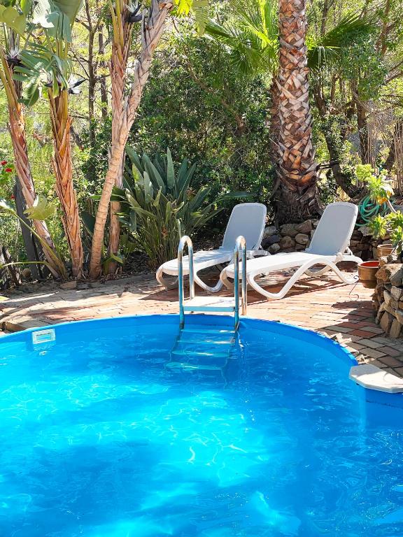 a swimming pool with two chairs and a swimming pool at Casa Mora, privater pool, Meerblick, toller Garten in Torrox