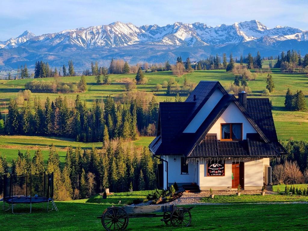 una casa en un campo con montañas en el fondo en Leszczyniański Domek en Biały Dunajec