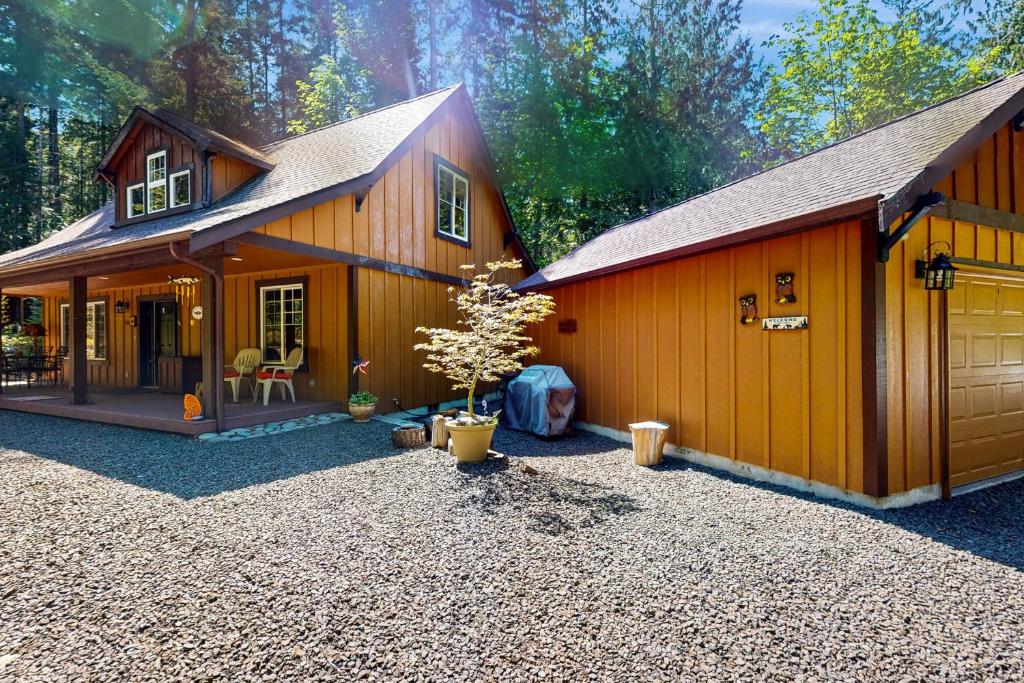 a large wooden house with a tree in the yard at Fireside Escape at Lake Cushman in Hoodsport