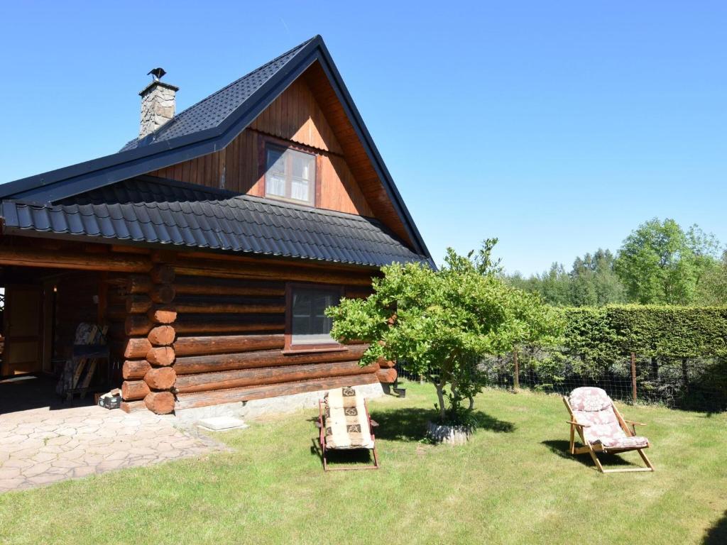 a log cabin with two chairs in front of it at Holiday home in Kopalino in Kopalino