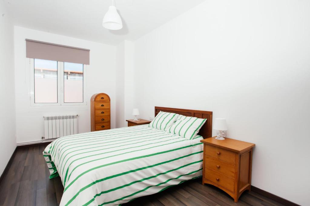 a white bedroom with a bed and two night stands at Apartamentos Florida 30 in Hernani