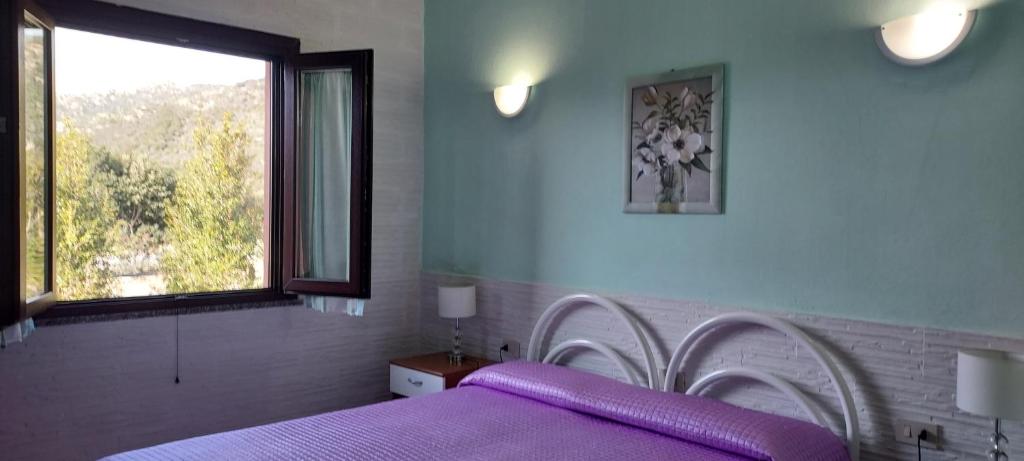 a bedroom with a purple bed and a window at La Rosa dei Venti B&B in Chia
