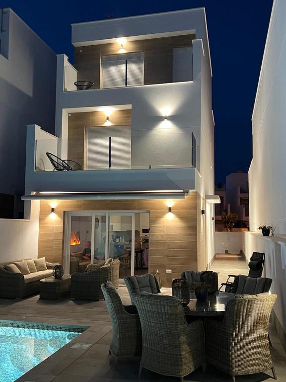 a building with a patio with chairs and a table at Modern new Pool Villa in San Pedro del Pinatar