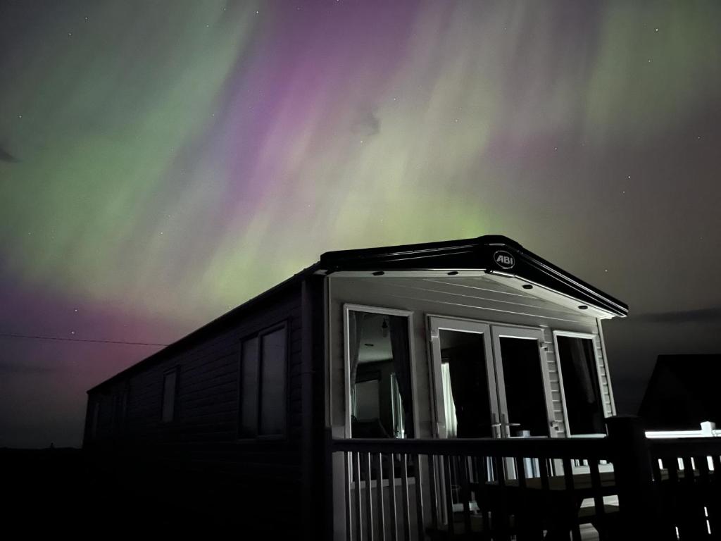 a house with the aurora in the sky at Robyn’s Nest in Lybster