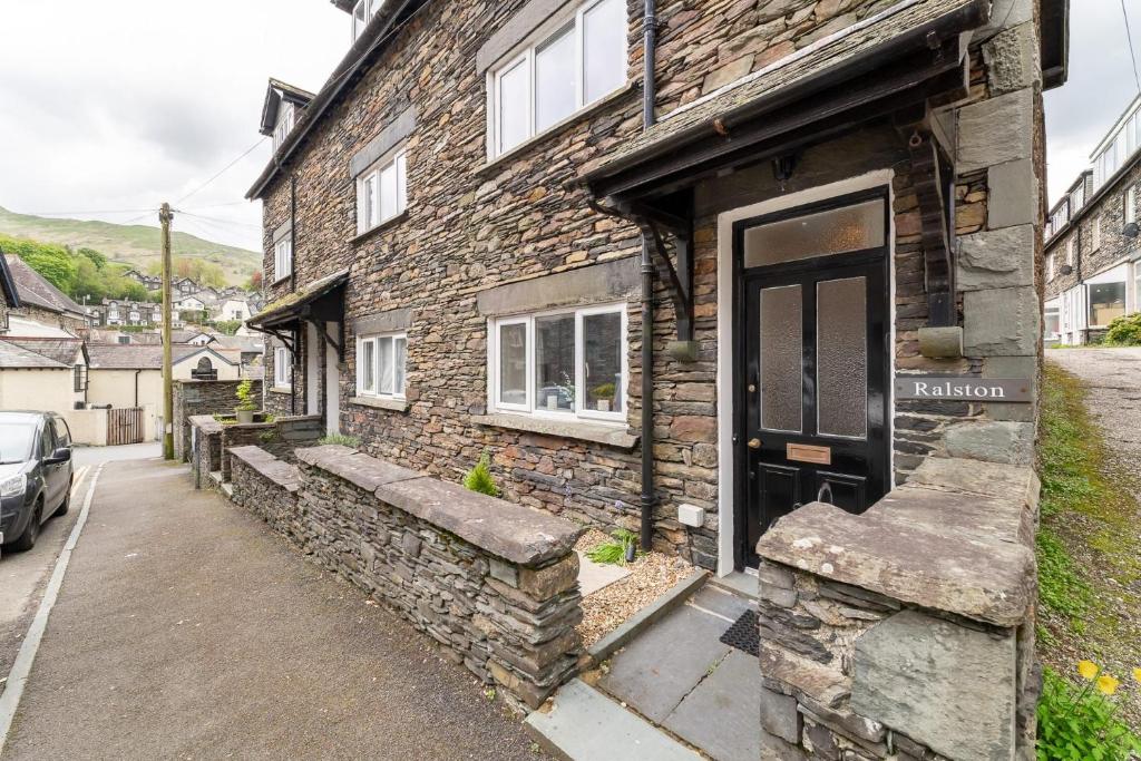 a stone house with a black door on a street at Ralston in Ambleside