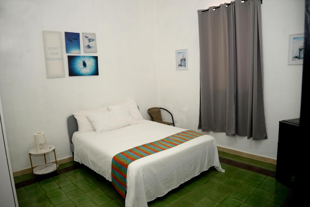 a bedroom with a white bed and a window at Hostal Mi Rincón in Santo Domingo