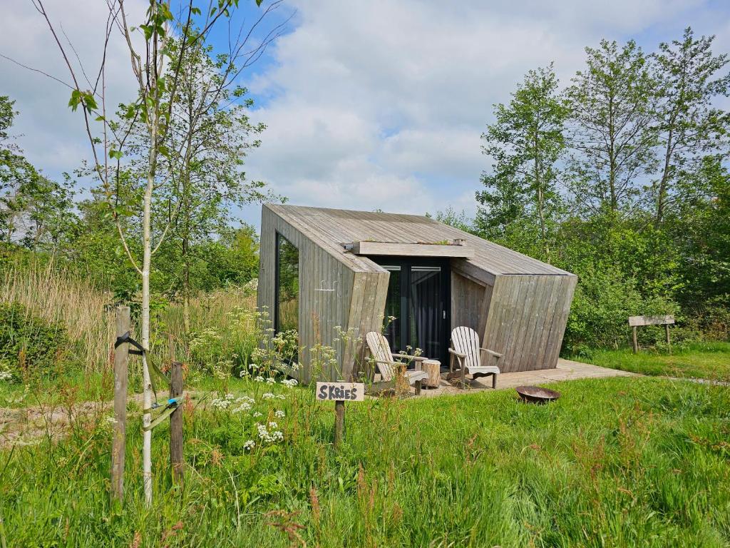 a small shed with two chairs in a field at Tiny House De Skries in Westergeest