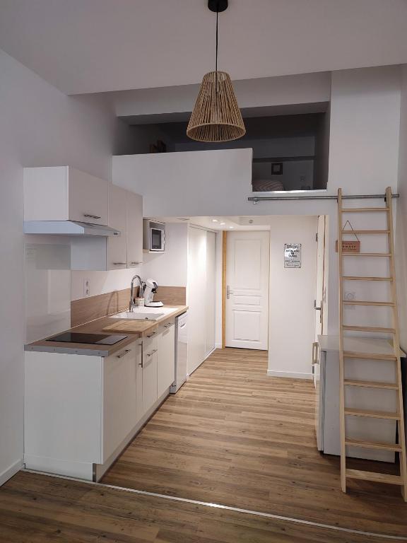 une cuisine avec des armoires blanches et un plancher en bois dans l'établissement Montpellier Gare St Roch, à Montpellier