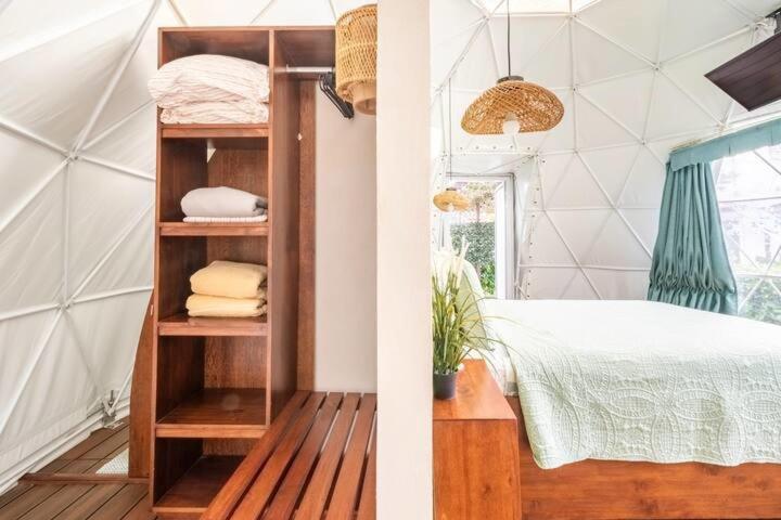 1 dormitorio con 1 cama y estante de libros con toallas en Ubuntu Glamping en Guanacaste