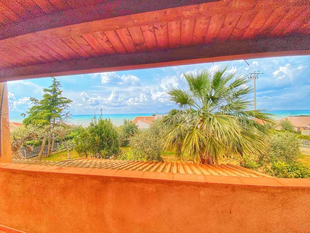uma vista para uma palmeira a partir de uma janela em Casa Margherita Cefalù - Villa con accesso privato al mare em Cefalù