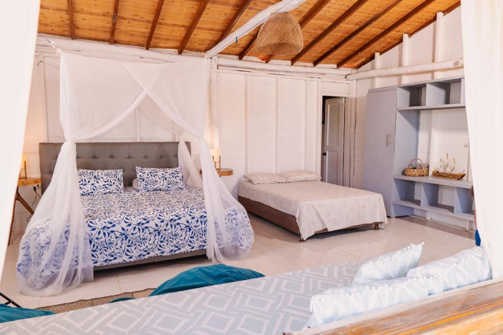 a bedroom with two beds and a canopy bed at Paraíso Natural Ecohotel in San Bernardo del Viento