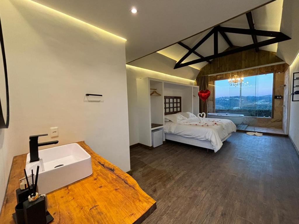 a bedroom with a bed and a sink and a window at Pousada Villa Dolce Amore - Boutique Hotel in Campos do Jordão