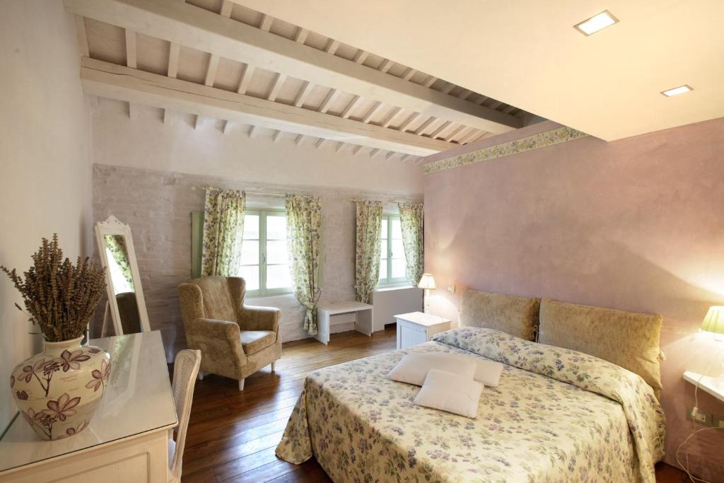 a large bedroom with a bed and a chair at Tenuta Santi Giacomo e Filippo in Urbino