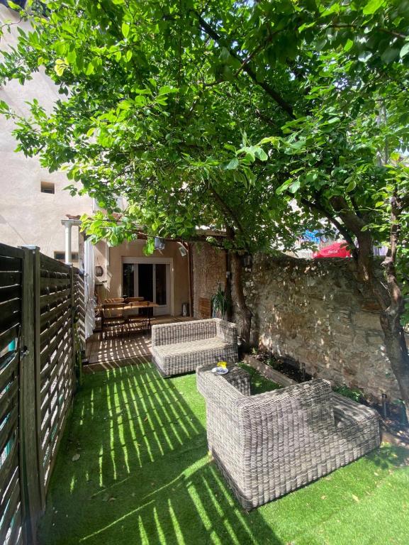 un patio avec deux chaises en osier blanc sous un arbre dans l'établissement Appartement T3 avec jardin, à Toulon