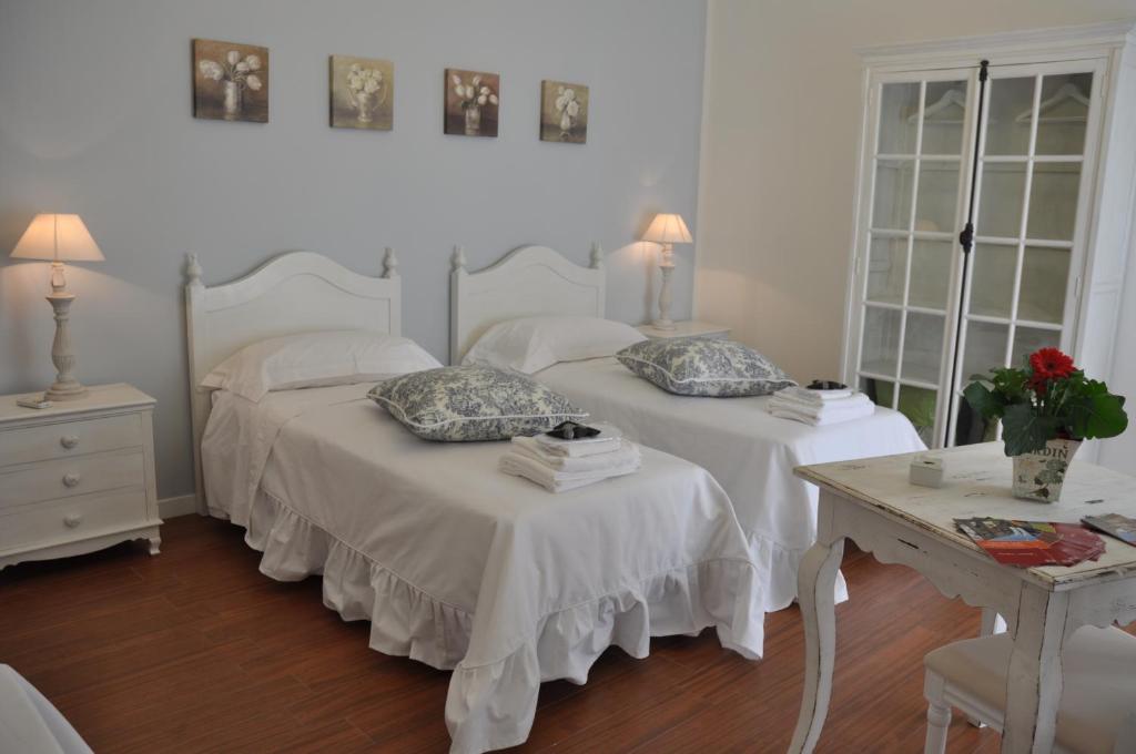 two beds in a bedroom with two tables and two lamps at Le stanze di Rebecca in Tor Vergata
