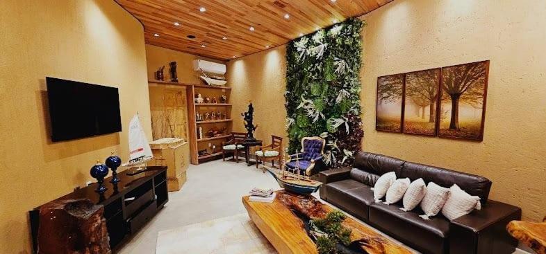 Una sala de estar con un sofá y un televisor. en Hotel Veneza, en Itabuna