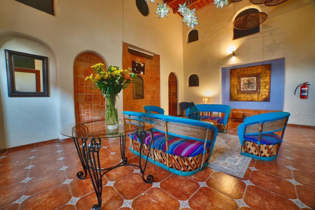 uma sala de jantar com uma mesa de vidro e cadeiras azuis em Hotel Casa Tequis San Luis Potosi em San Luis Potosí