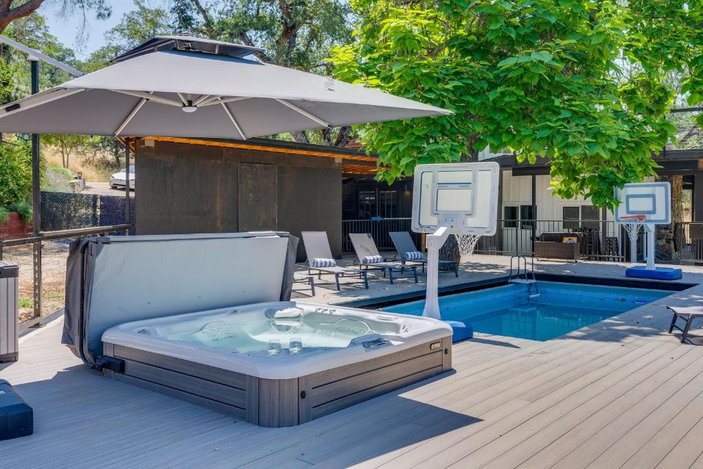 a hot tub with an umbrella next to a pool at Updated Three Rivers Vacation Rental with Gas Grill in Three Rivers
