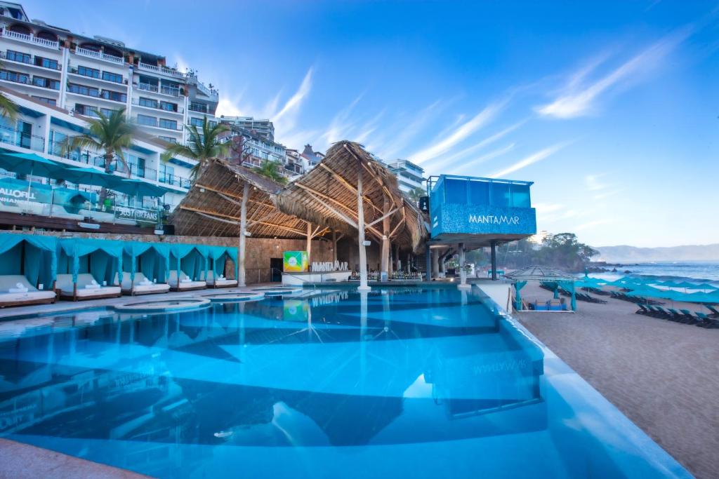 una piscina en la playa con un hotel en el fondo en Almar Resort Luxury LGBT Beach Front Experience en Puerto Vallarta