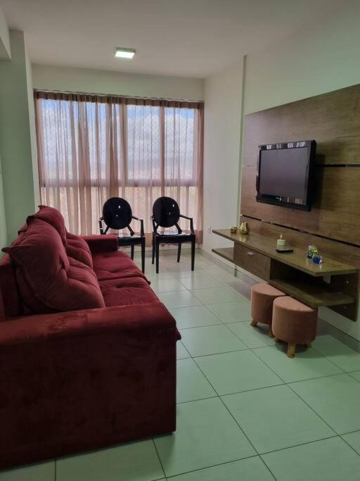 a living room with a red couch and a flat screen tv at Apto próximo ao Pátio do Forró in Caruaru