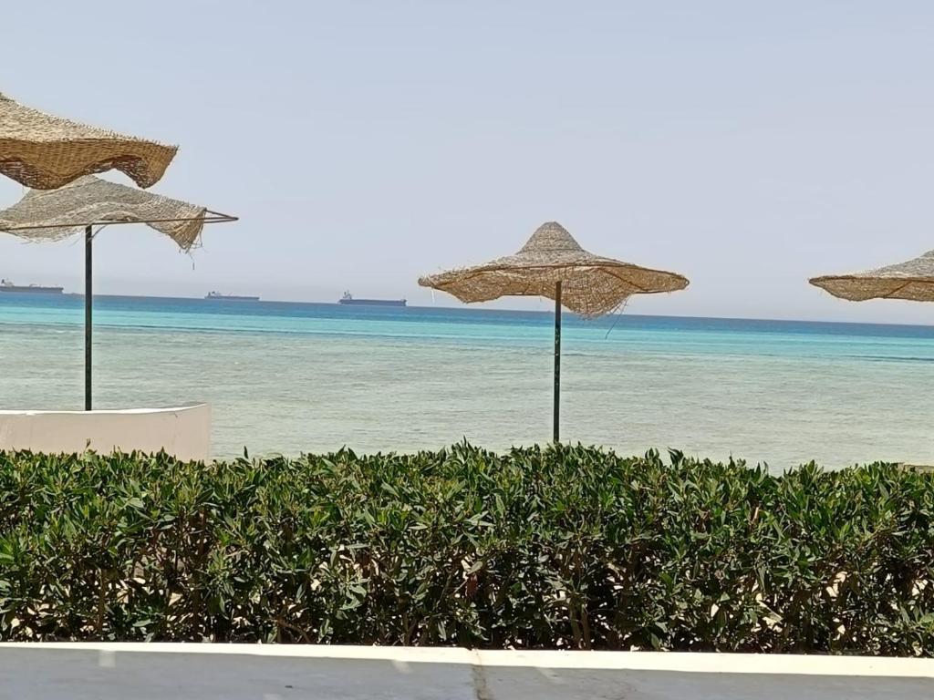 three straw umbrellas on a beach with the ocean at شاليه سياحي مكيف صف أول علي البحر مباشره ومكيف وبحديقه خاصه in Ras Sedr