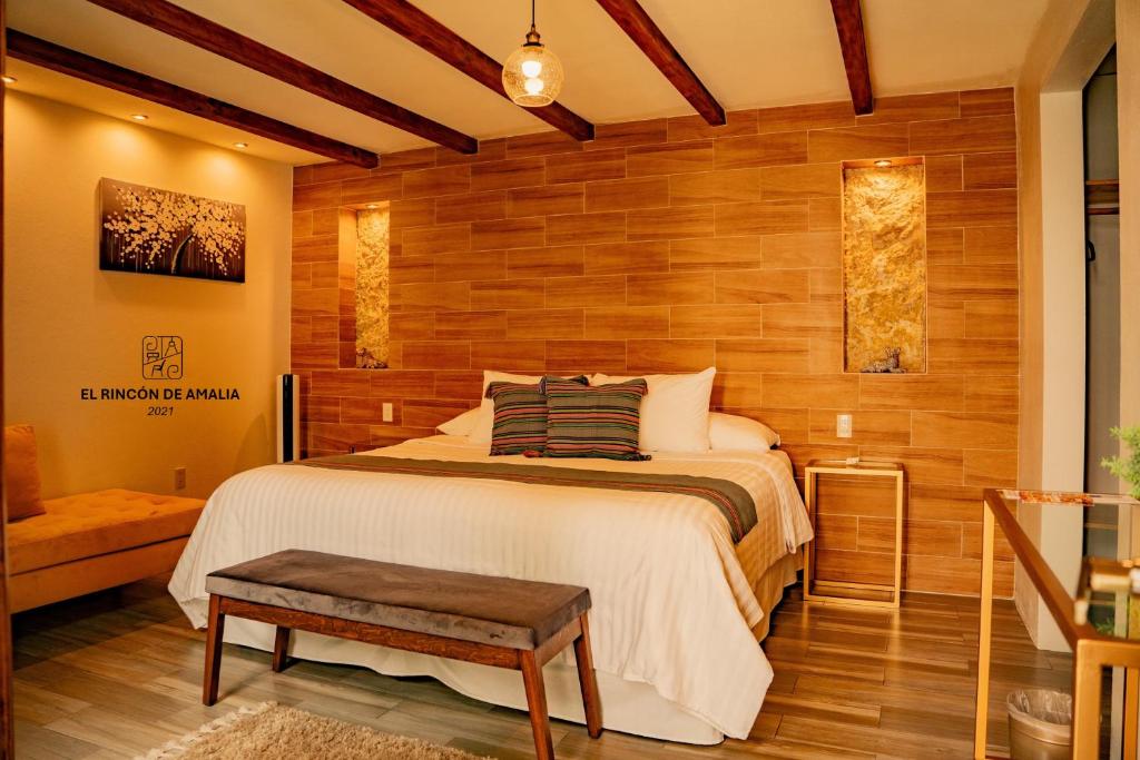 1 dormitorio con 1 cama grande y pared de madera en El Rincón de Amalia en San Cristóbal de Las Casas