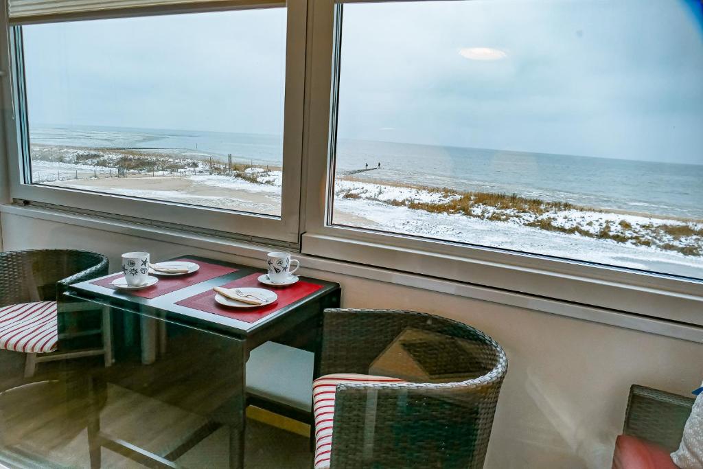 a table and chairs in a room with a view of the ocean at Haus Seehund HD04 in Cuxhaven