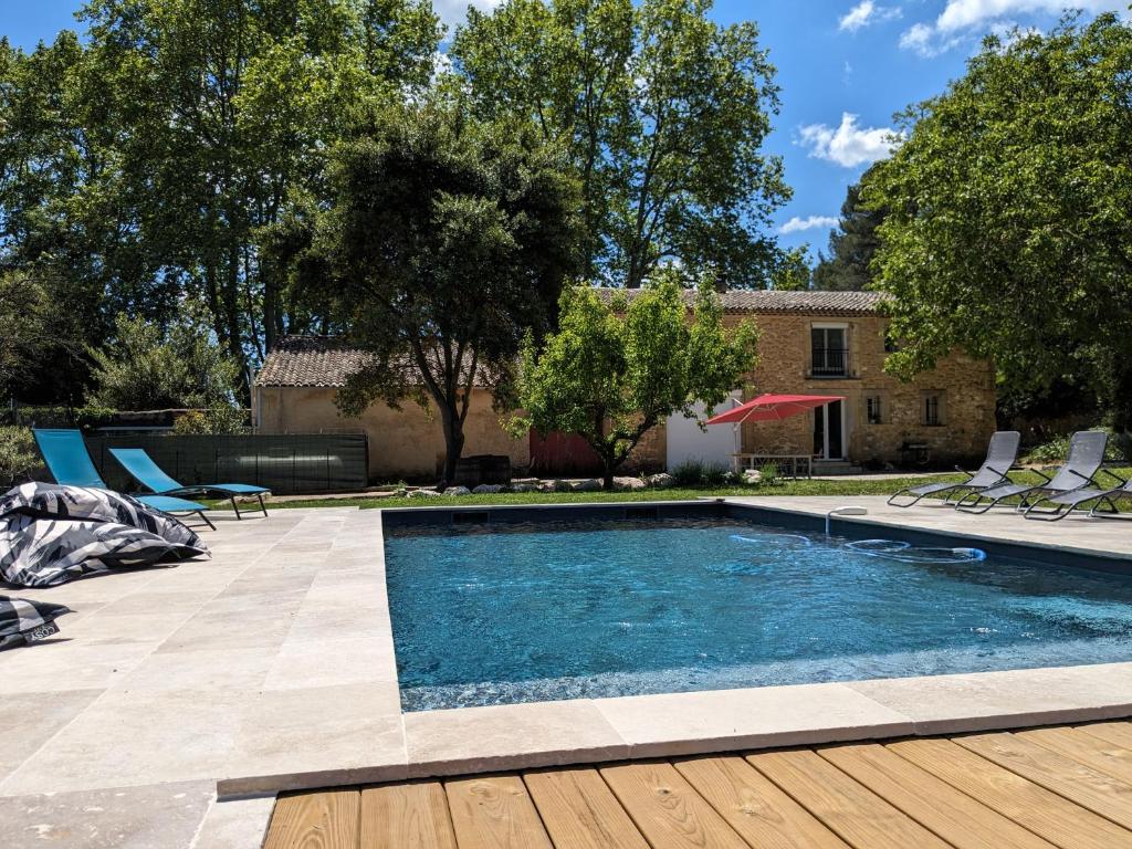 una piscina en un patio con sillas y árboles en La ferme du TourreBlanc, en Lambesc