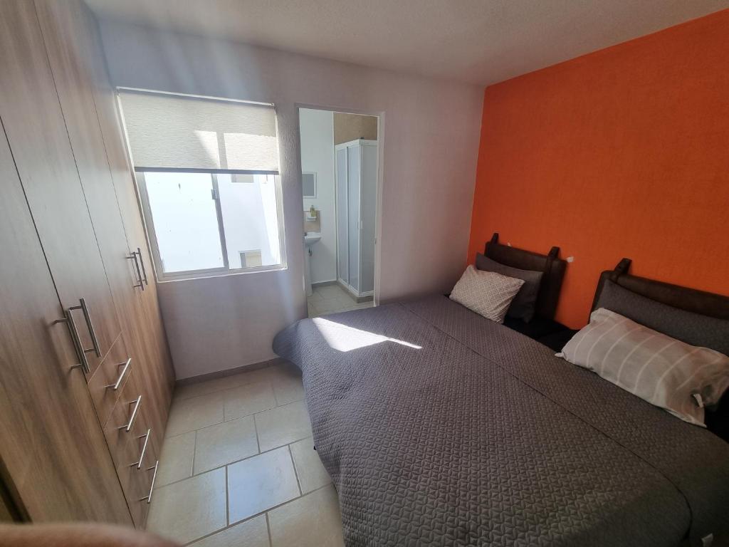 um quarto com uma cama e uma parede laranja em Departamento con Alberca San Jose em Querétaro