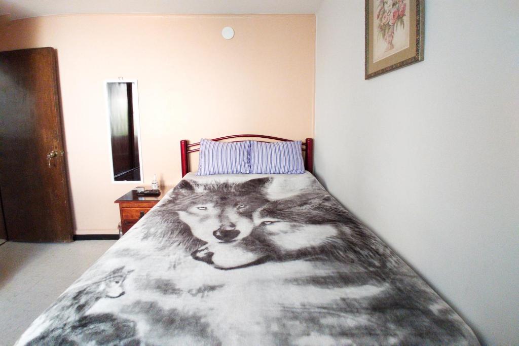 a bed in a bedroom with a wolf blanket at Acogedora habitación doble a 5 min del Aeropuerto CDMX in Mexico City