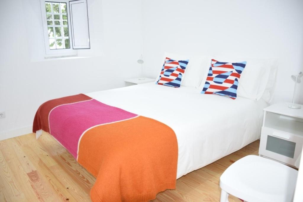 a bedroom with a white bed with an orange blanket at Cool Tailor Made 2 Bedroom Apartment in Lisbon
