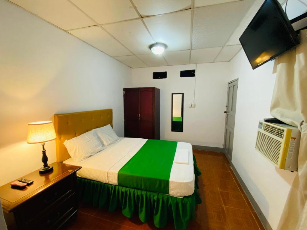 een kleine slaapkamer met een bed en een televisie bij Hostal Pochote in León