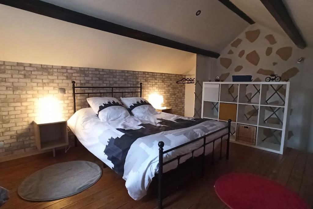 une chambre avec un grand lit et un mur de briques dans l'établissement Charmante petite maison meublée, à Le Vernet
