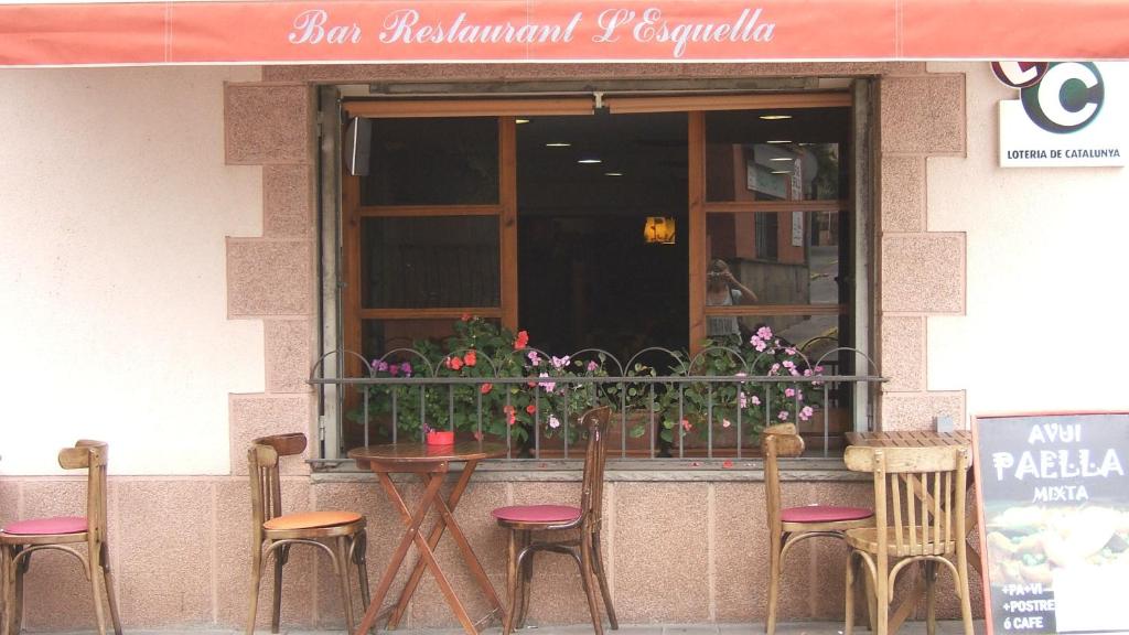 un grupo de sillas y una mesa frente a una ventana en Hostal L'Esquella, en Aiguafreda