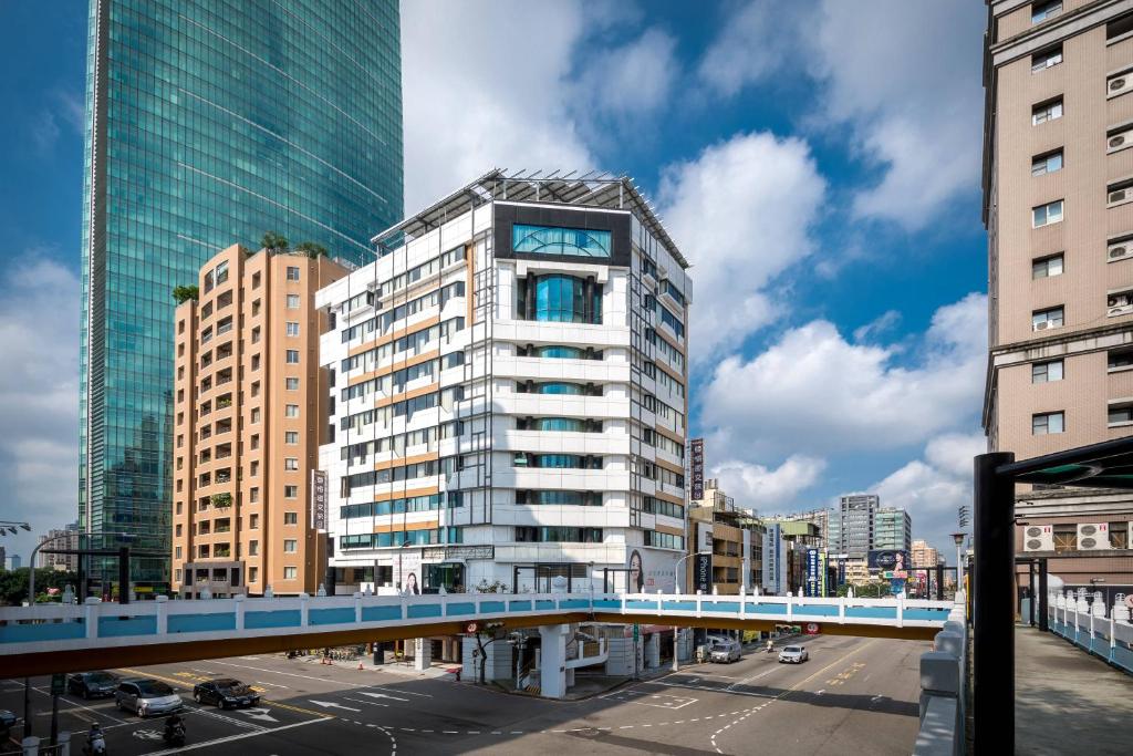 a tall building with a bridge over a street at Calligraphy Greenway Hotel in Taichung